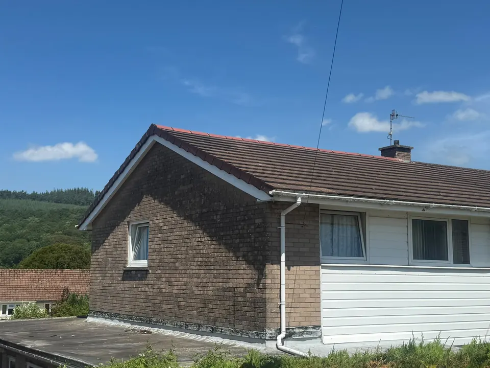 Brick bungalow with a concrete tiled roof and a flat roof section beside it