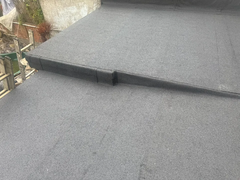 New grey mineral felt flat roof with a stepped upstand between two levels, by Efficient Roofing