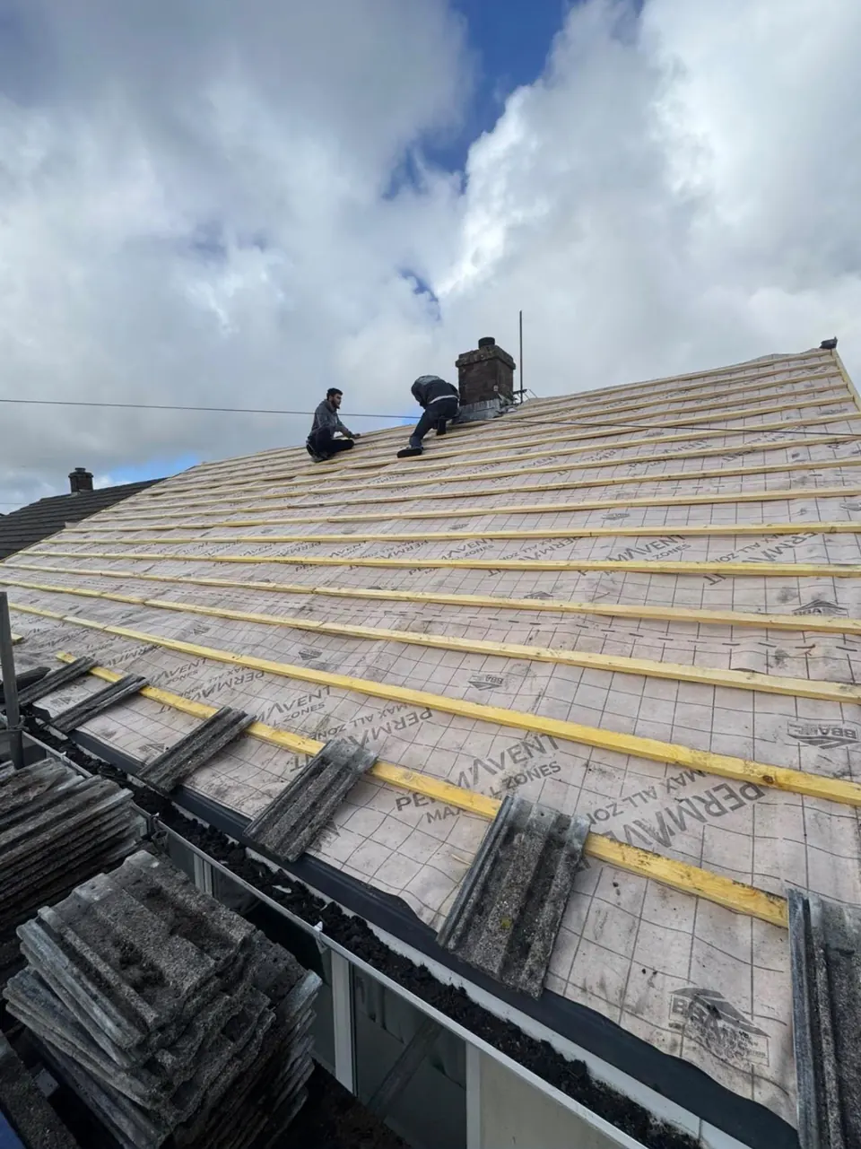 Roof stripped back to new breathable membrane and fresh battens, roofers at the ridge