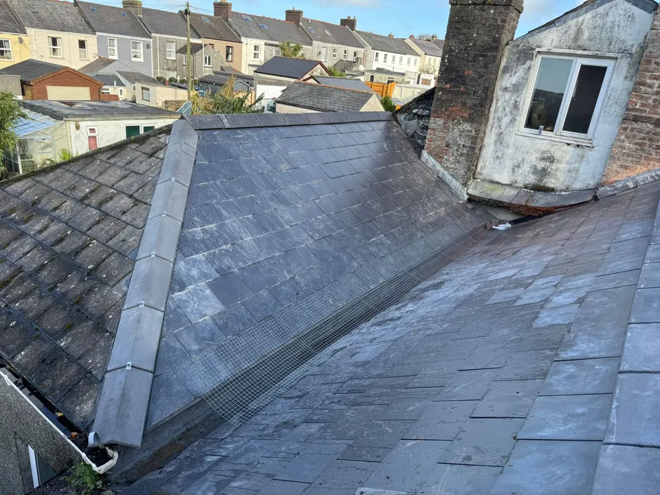 Slate roof with new slates and a new hip running up to a dormer and chimney